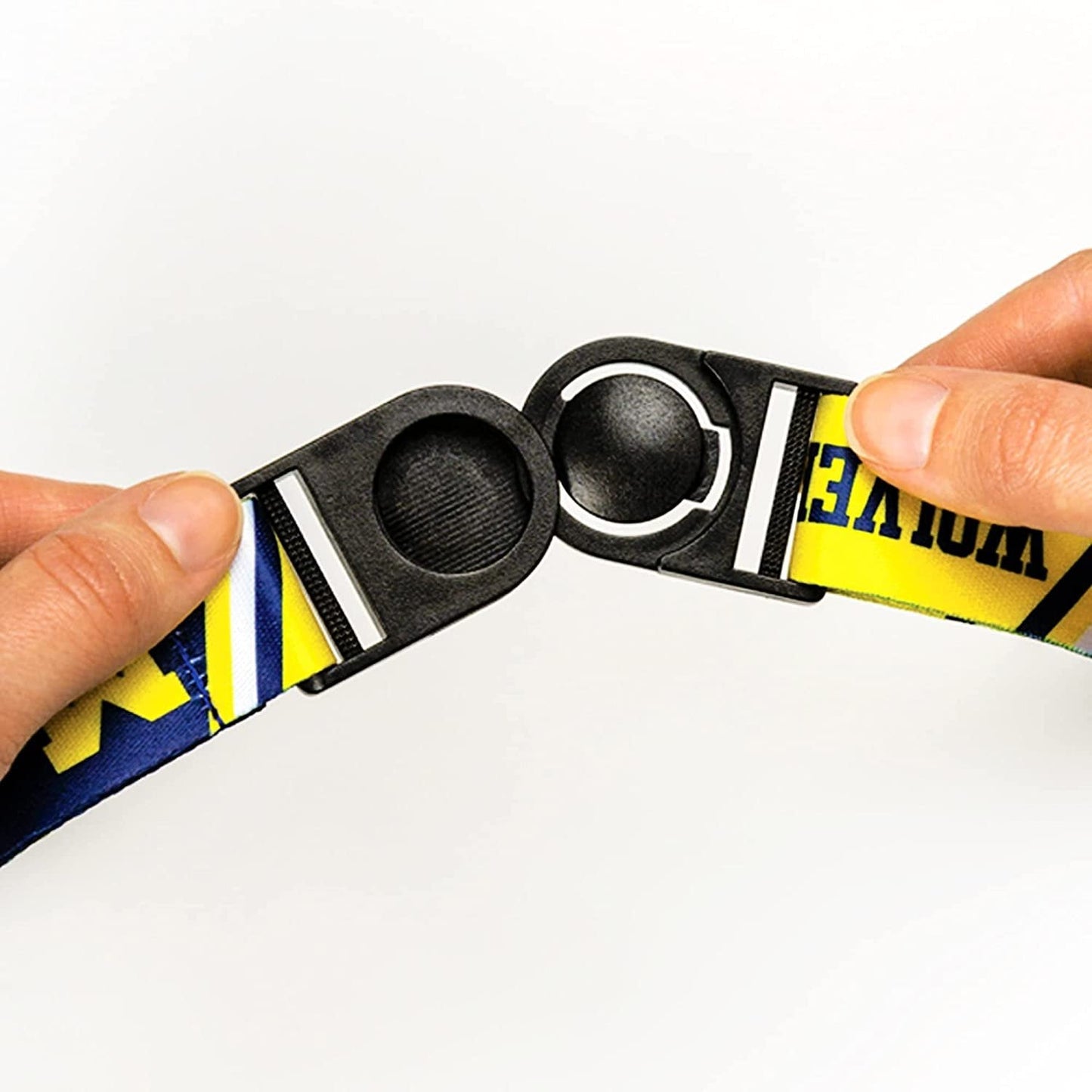 Close-up of a person holding a black and yellow belt with a metal buckle on a white background
