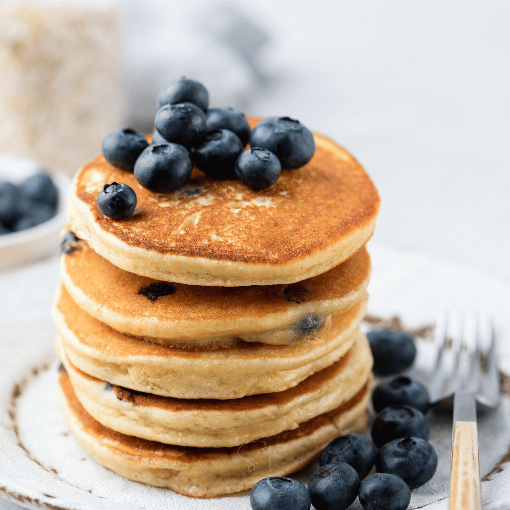Stack of pancakes with blueberries on a white plate