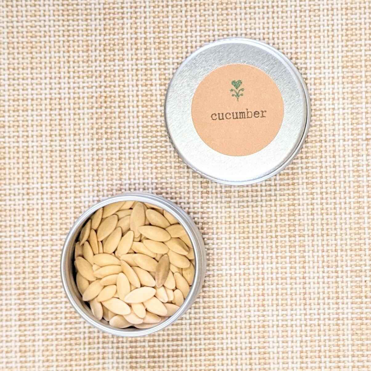 Silver tin with 'cucumber' label on lid containing white seeds on beige woven background