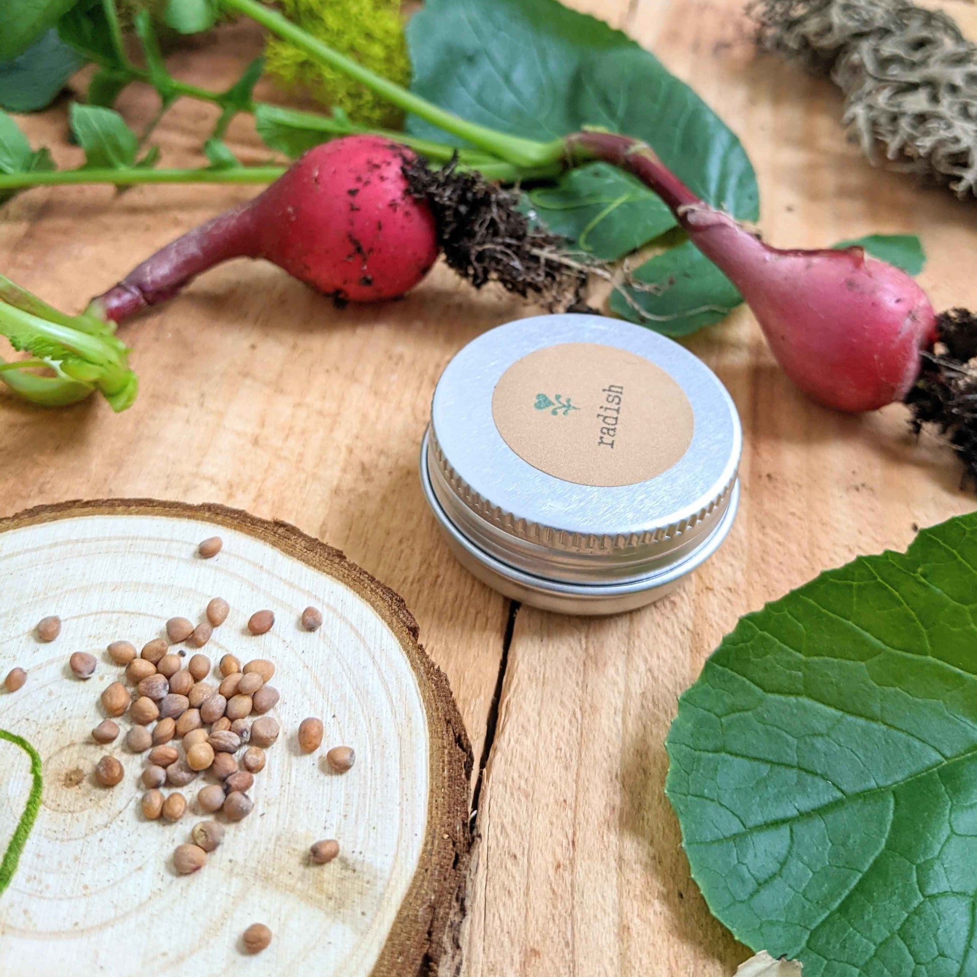Small container with a lid featuring a brand logo, surrounded by radishes and leaves on a wooden surface.
