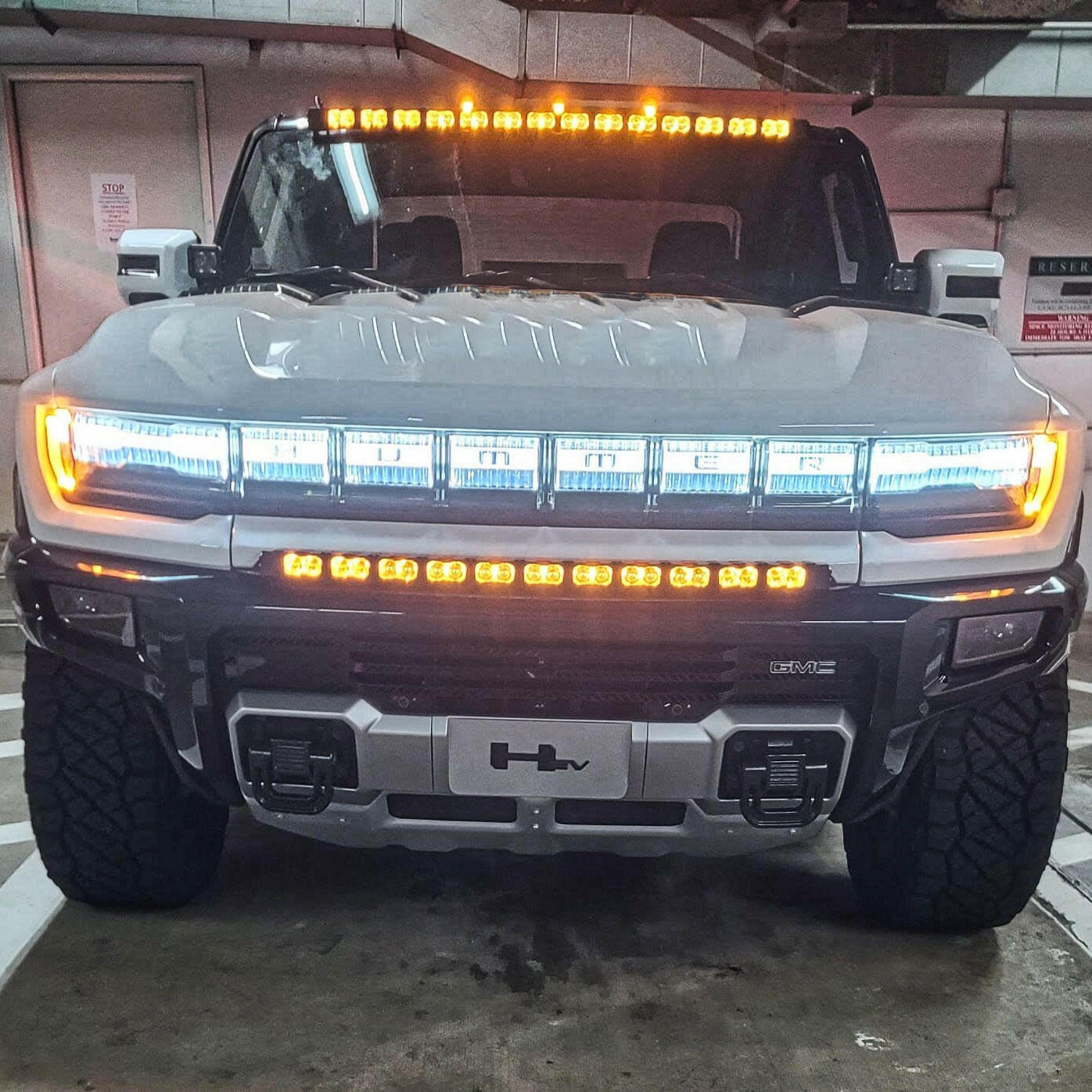 Front view of a large truck with illuminated light bars in a garage.