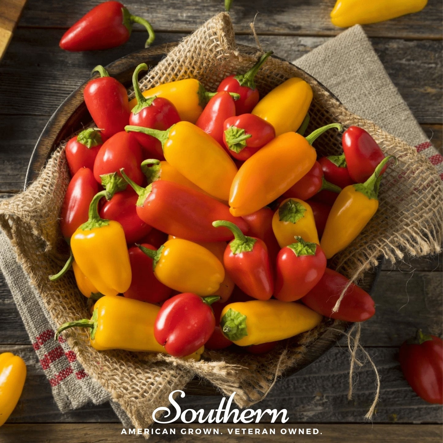 Assorted red and yellow peppers in a woven basket on a wooden surface with 'Southern' branding.