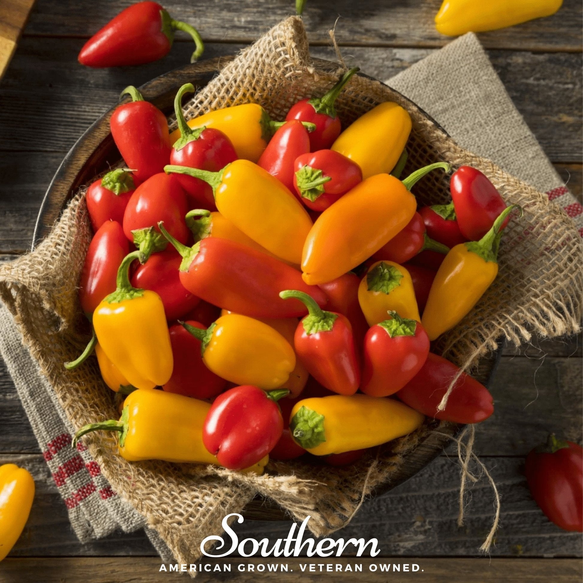 Assorted red and yellow peppers in a woven basket on a wooden surface with 'Southern' branding.