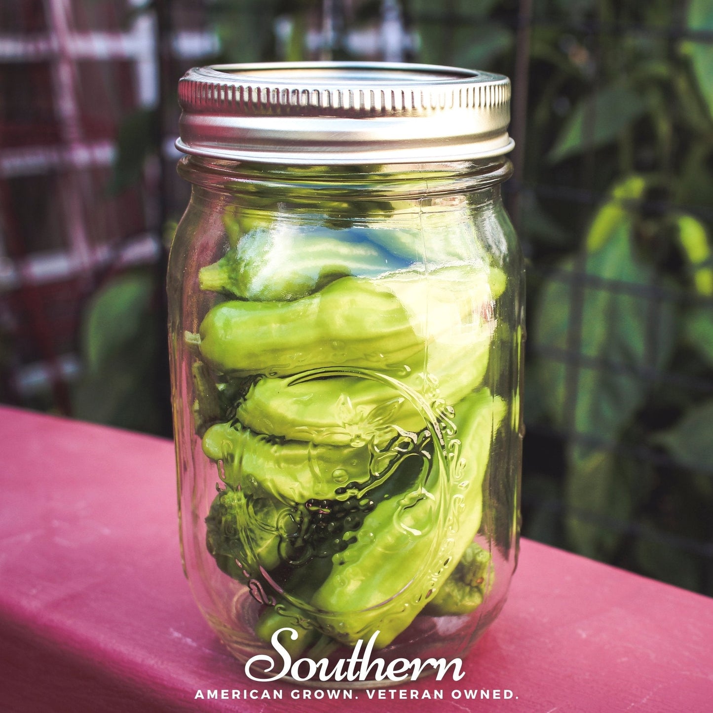 Mason jar filled with green peppers on a pink surface with 'Southern' branding.