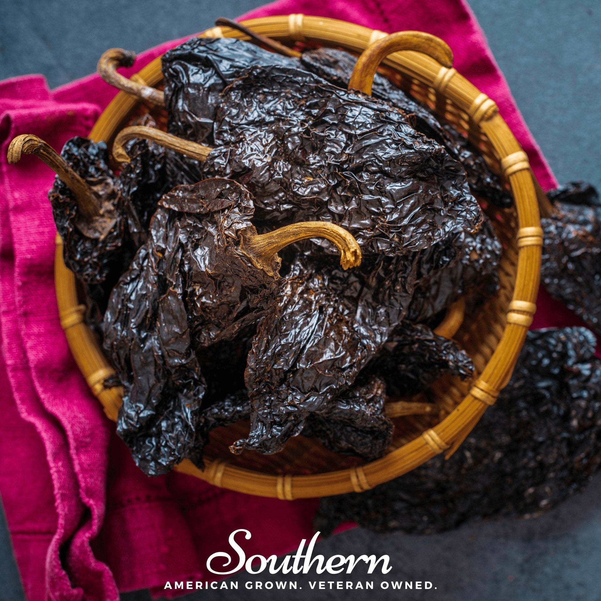Dried chiles in a wooden basket on a pink cloth with 'Southern' branding.