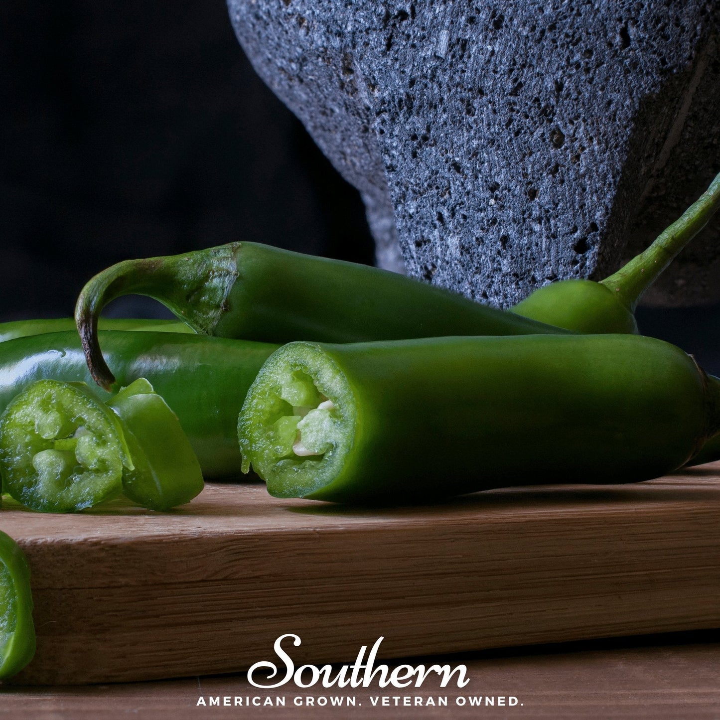 Green peppers on a wooden cutting board with a dark background