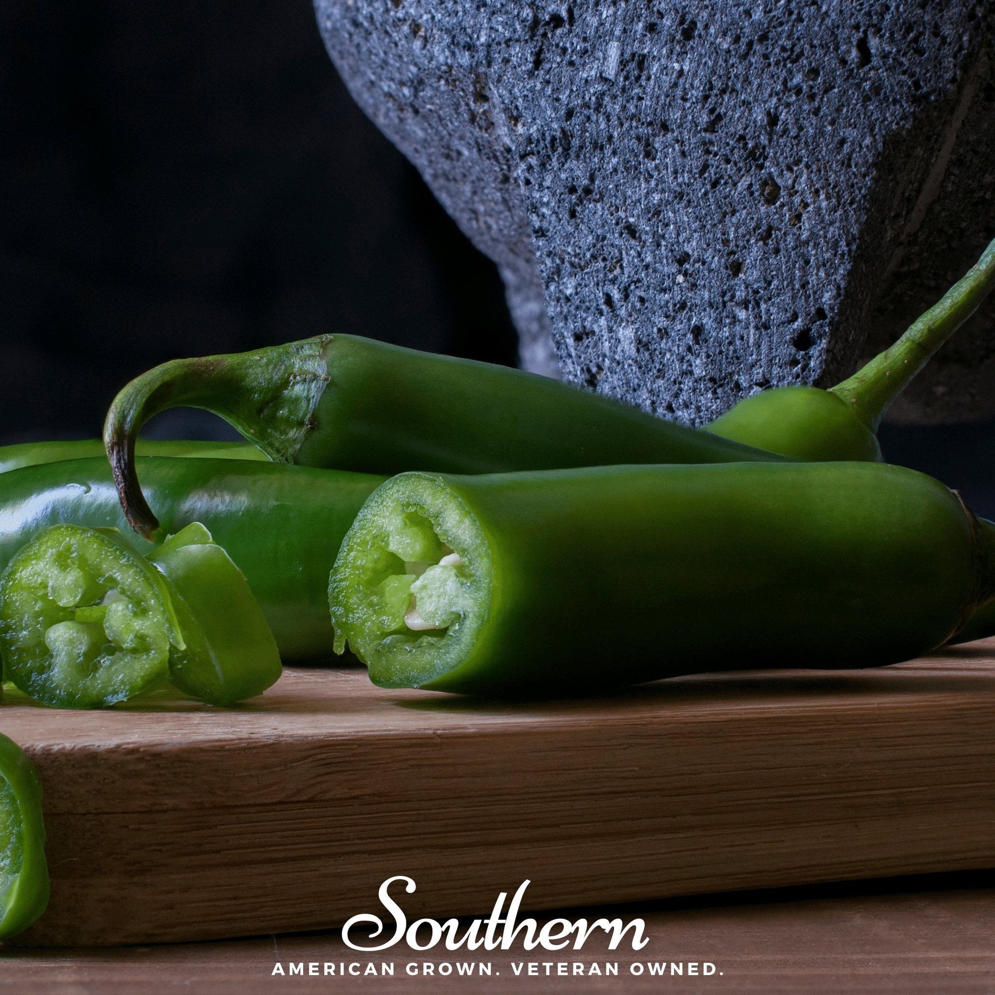 Green peppers on a wooden cutting board with a dark background