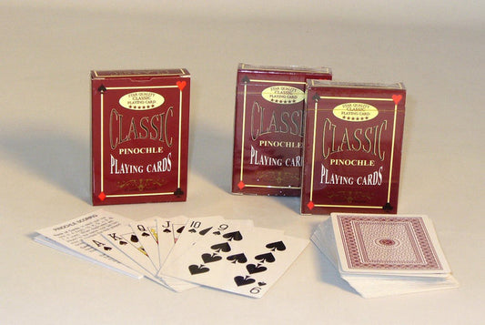 Three boxes of Classic Pinochle Playing Cards on a gray surface with some cards spread out.