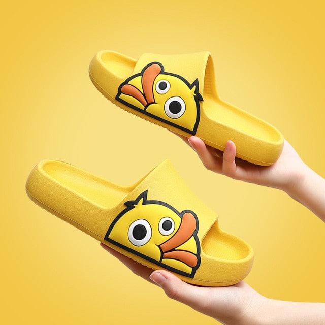 Yellow slippers with cartoon face design held against a yellow background