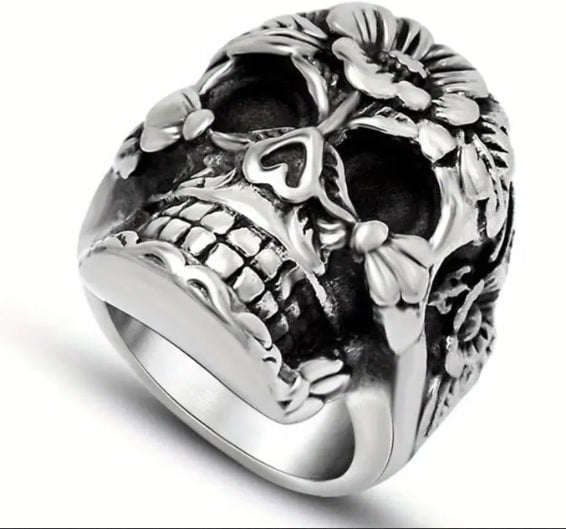 Silver skull ring with floral designs on a white background
