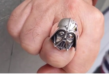 Silver Darth Vader ring on a person's finger with a neutral background