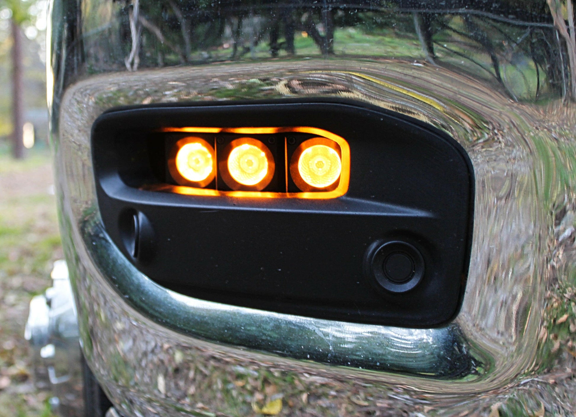 Close-up of a vehicle's front bumper with a small light assembly.