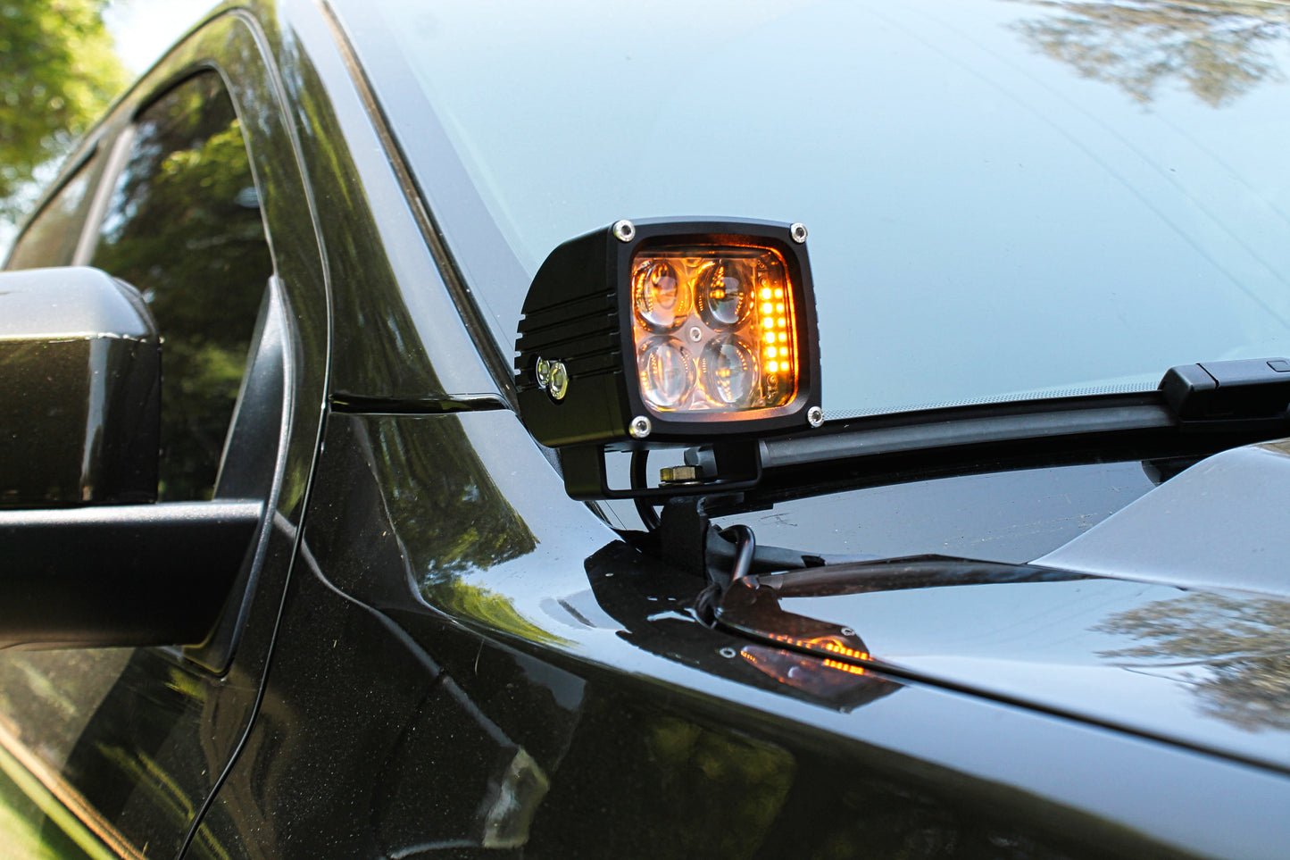 Side view of a car with an additional amber LED light mounted by the mirror