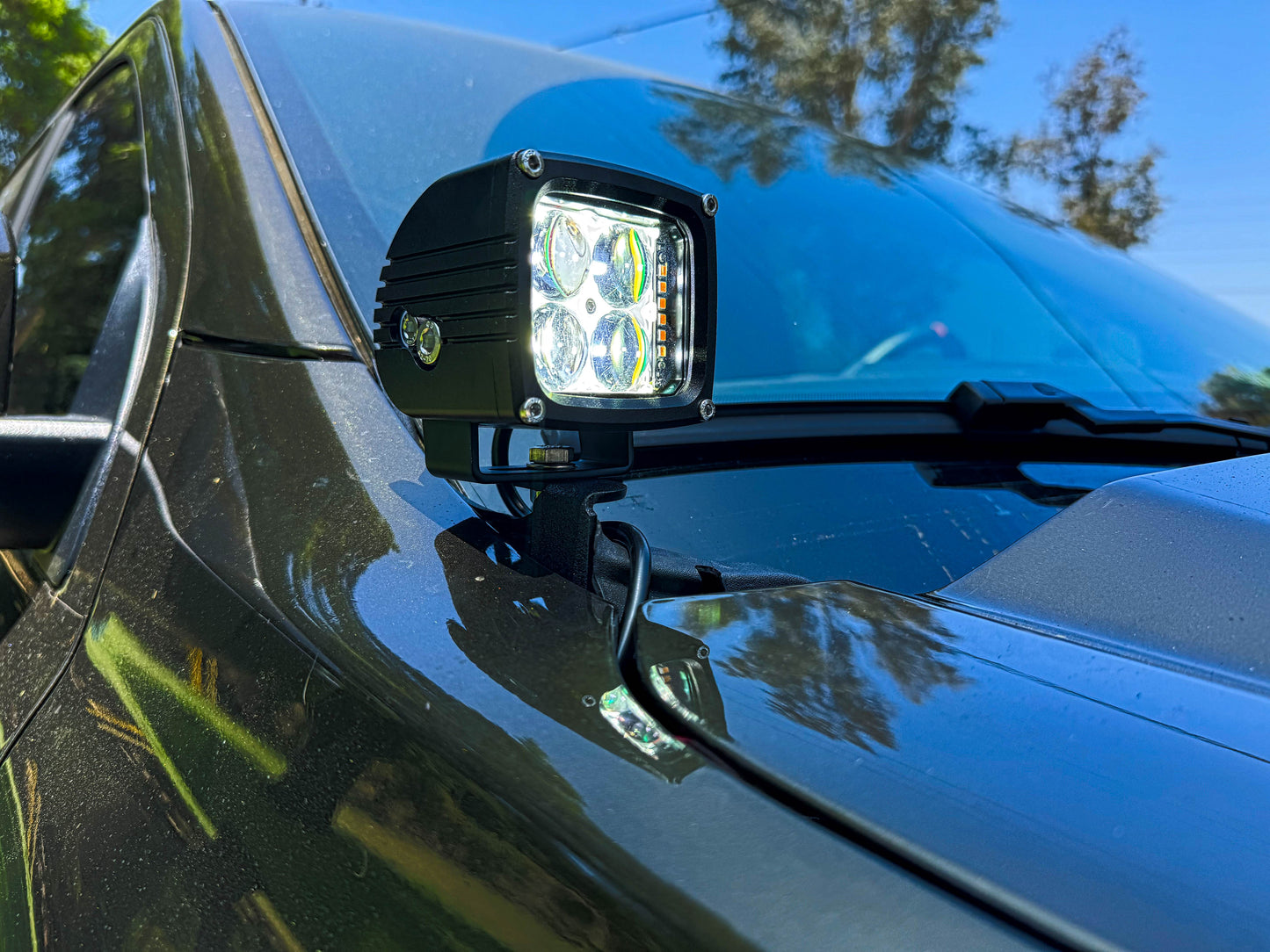 LED light bar mounted on a vehicle's hood with trees in the background
