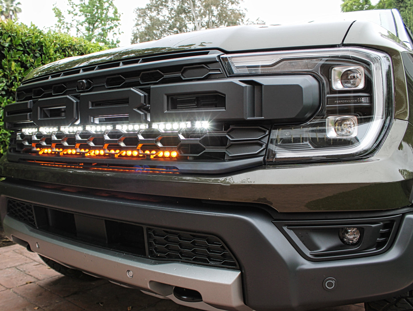 Close-up of a Ford truck's front grille with illuminated LED lights.