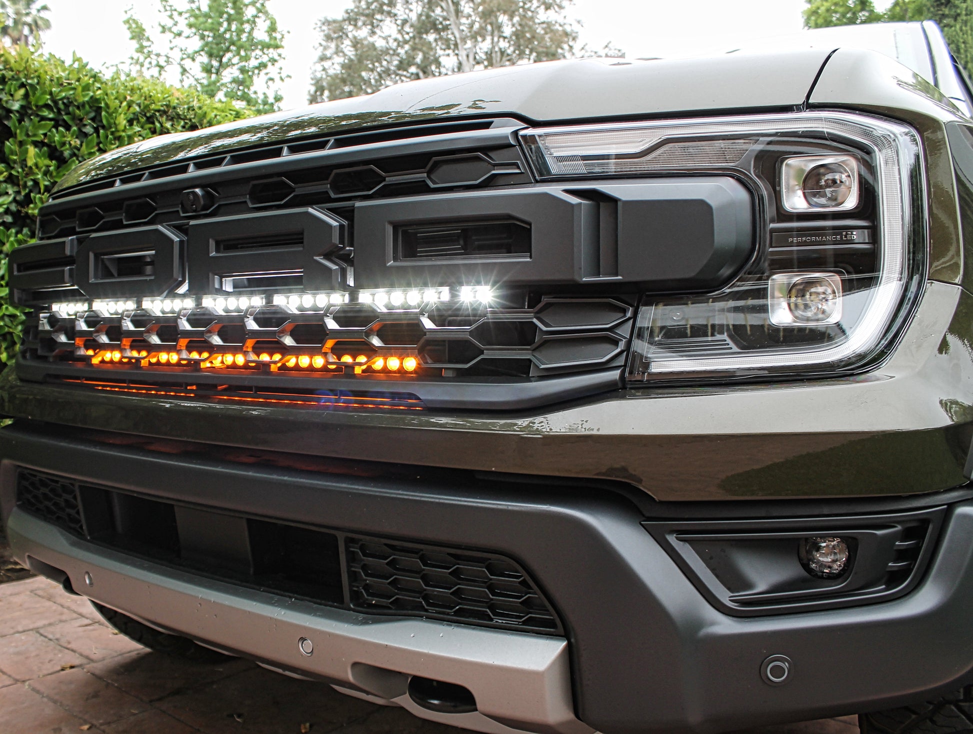 Close-up of a Ford truck's front grille with illuminated LED lights.