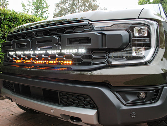 Close-up of a Ford truck's front grille with illuminated LED lights.