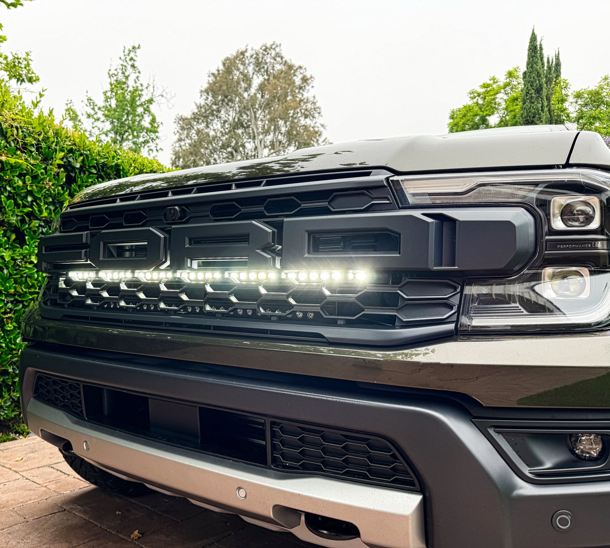 Close-up of a Ford truck grille with LED lights in an outdoor setting.