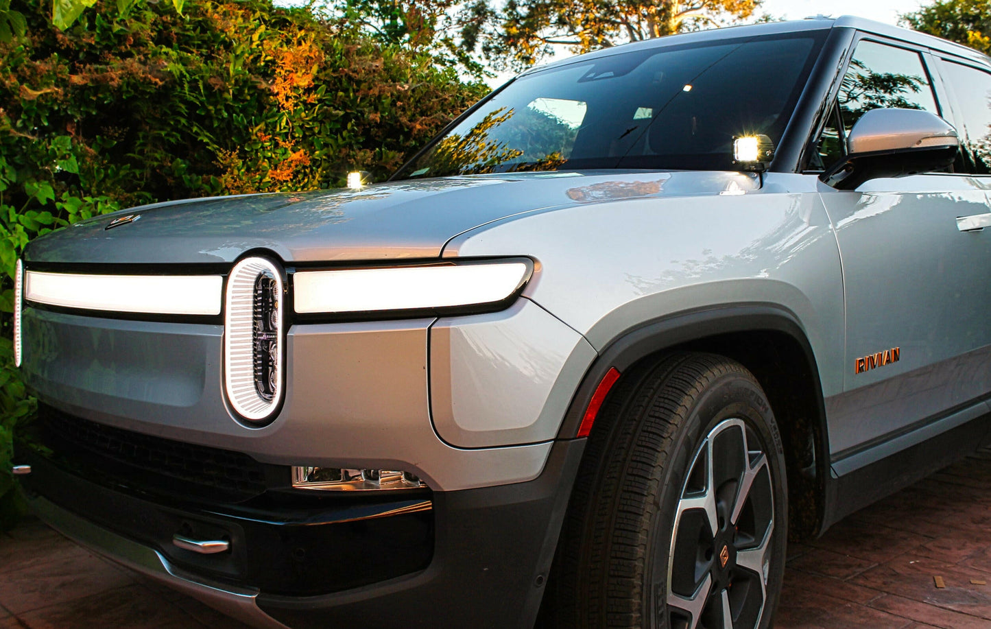 Silver Rivian electric vehicle with unique headlights parked outdoors
