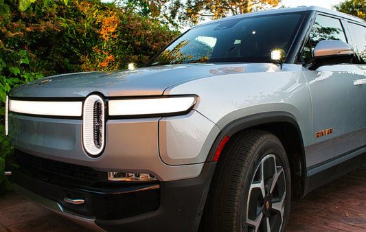 Silver Rivian electric vehicle with unique headlights parked outdoors