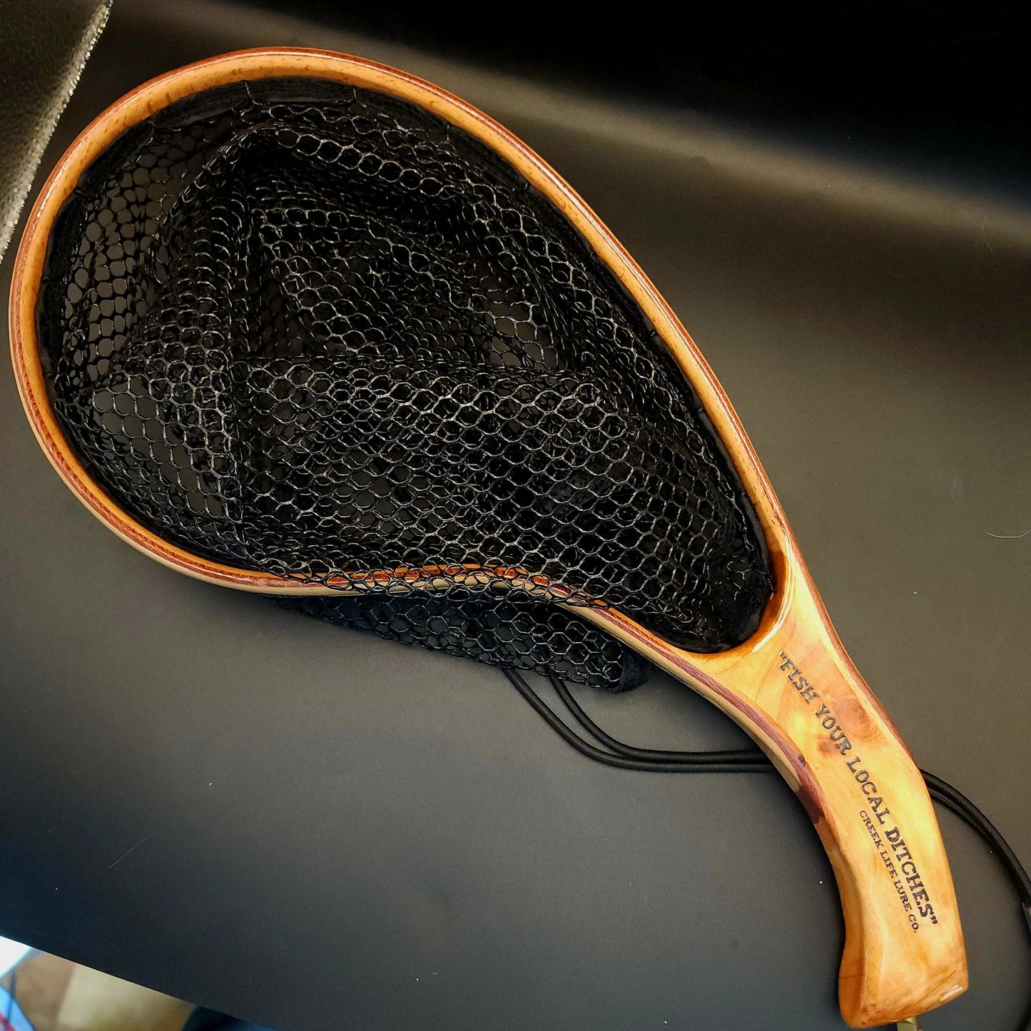 Fishing net with wooden handle on a dark surface
