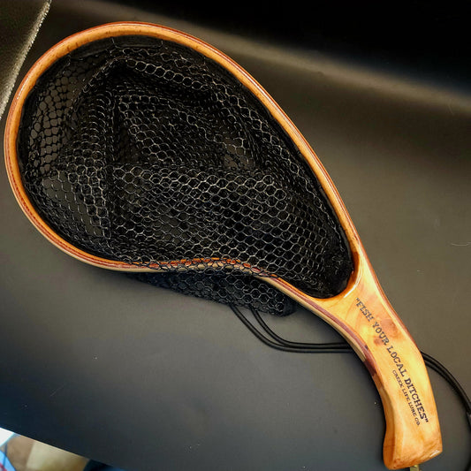 Fishing net with wooden handle on a dark surface