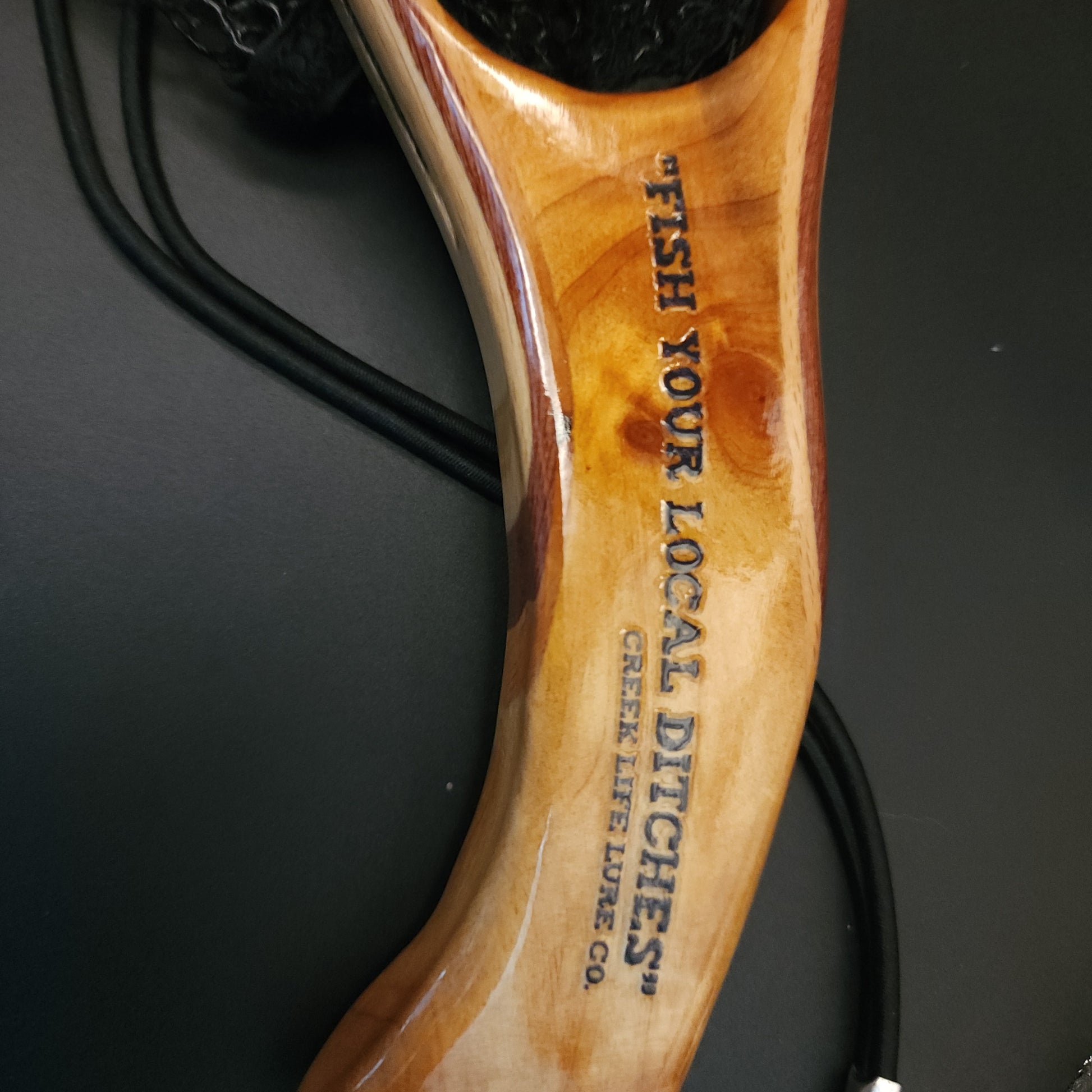 Wooden fishing net handle with engraved text on a black background