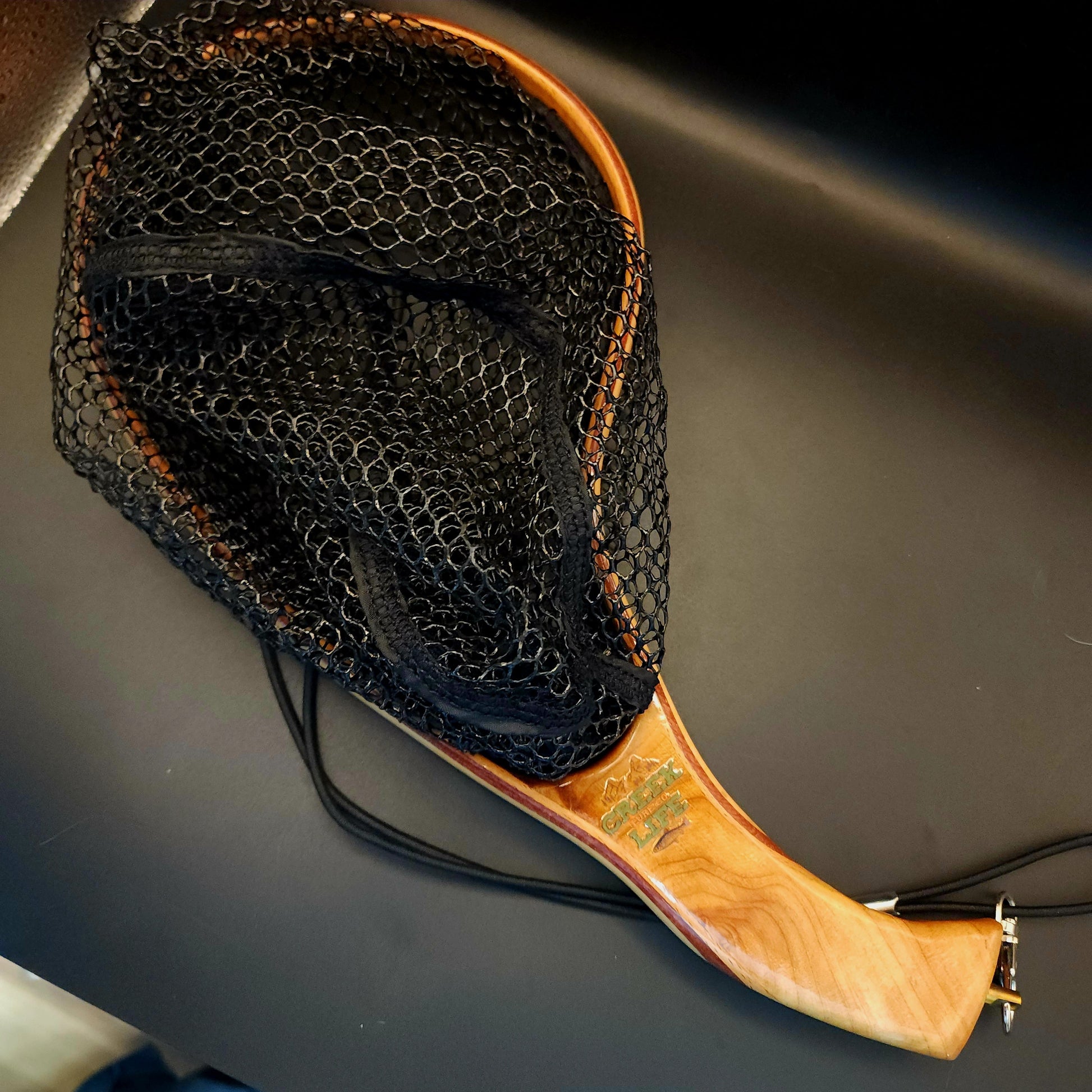 Fishing net with wooden handle on a dark surface