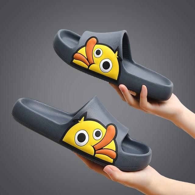Gray slides with cartoon fish design held by hands against a dark background