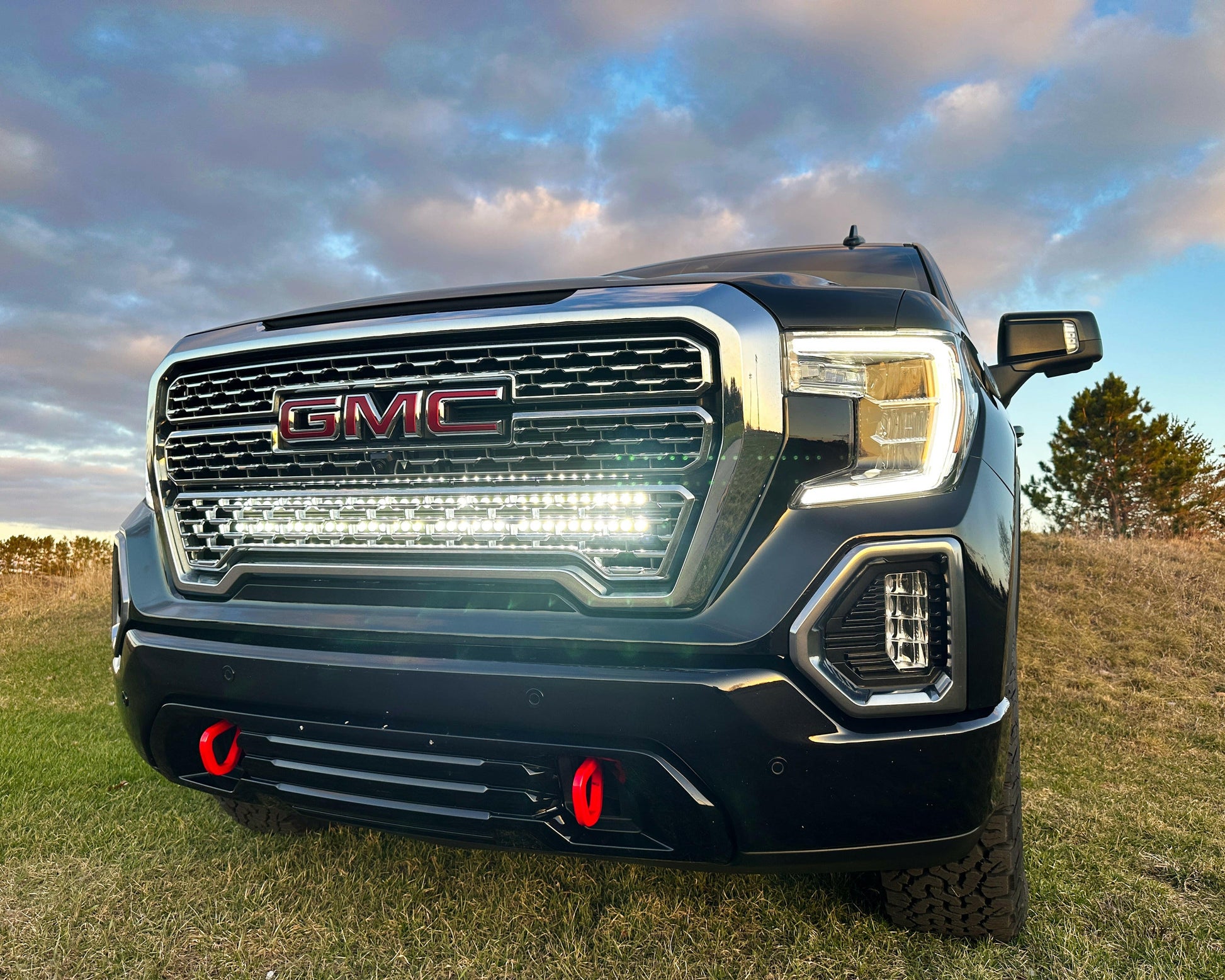 GMC truck with Light Bar in a field with a cloudy sky