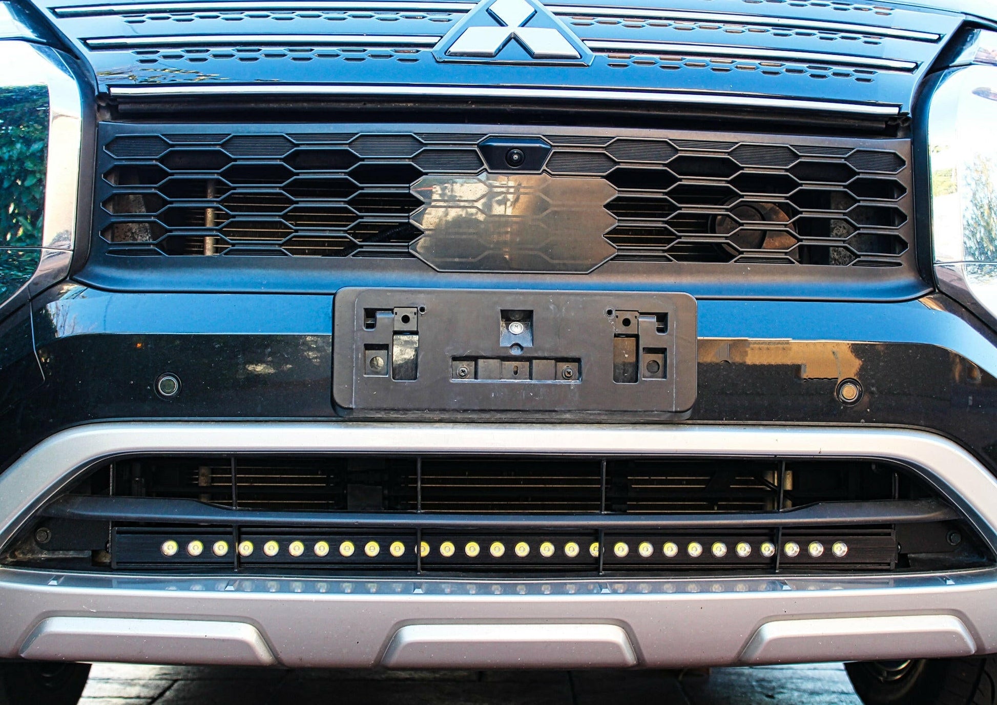 Close-up of a blue truck's front grille with light bar mounted
