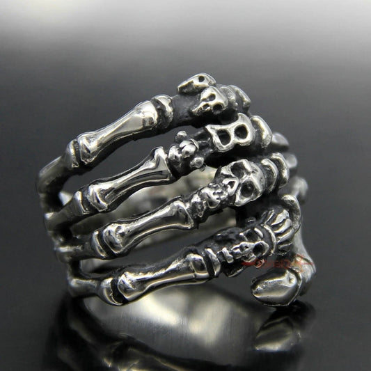 Silver skeleton hand ring on a reflective black surface