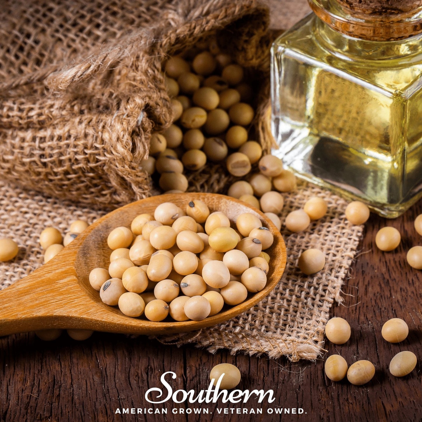 Soybeans in a wooden spoon with a bottle of soybean oil on a rustic wooden surface.