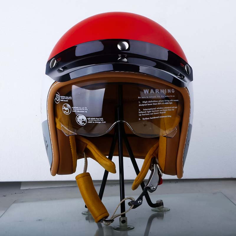 Red motorcycle helmet with visor on a stand against a white background
