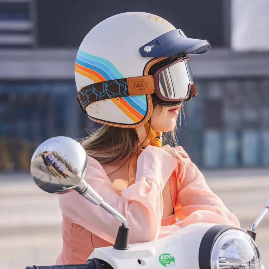 Person wearing a colorful helmet and goggles on a scooter