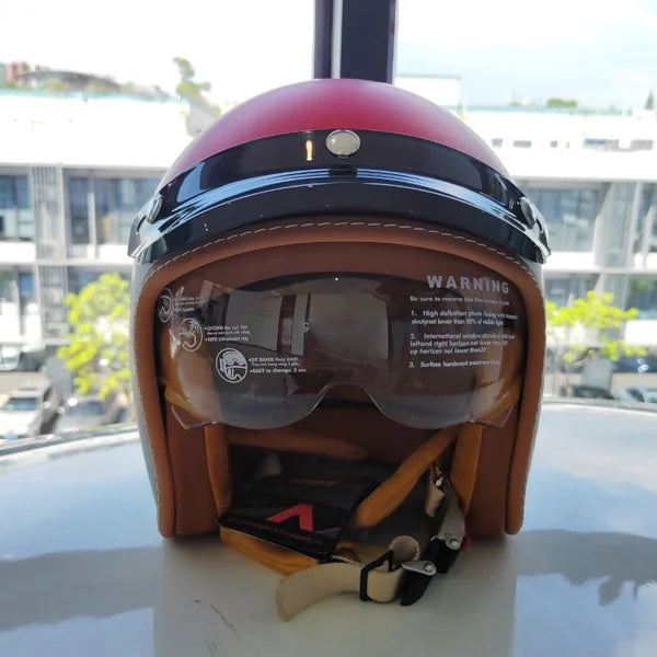 Helmet with visor and warning label on a reflective surface with a blurred outdoor background