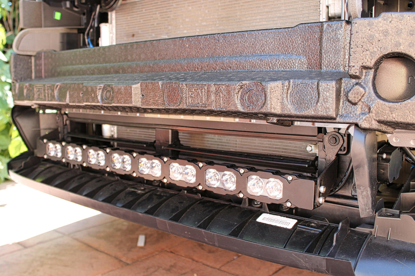 Close-up of a vehicle's front bumper with LED lights and a textured grille.