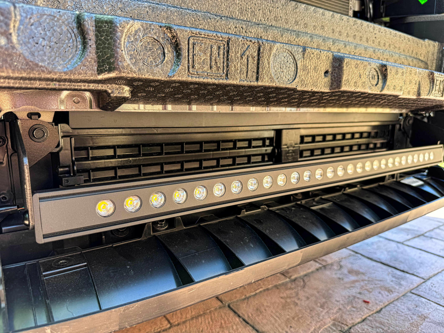 Close-up of a vehicle undercarriage with visible branding and lighting components.