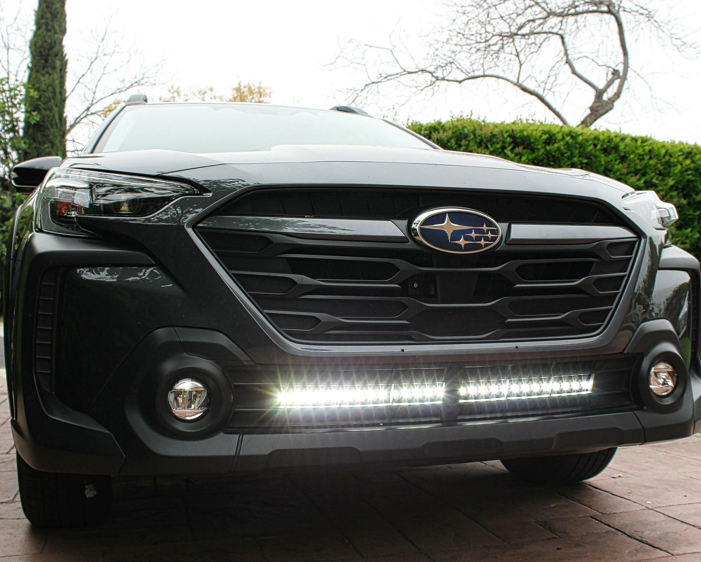 Front view of a black Subaru vehicle with a light bar on a driveway.
