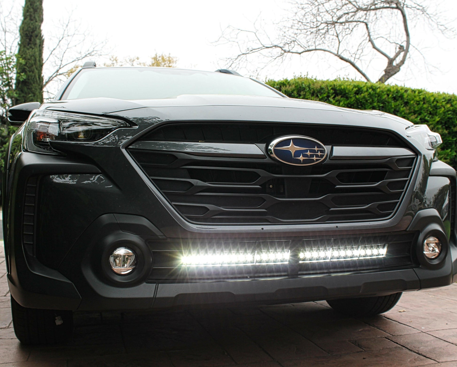 Front view of a black Subaru vehicle with a light bar on a driveway.