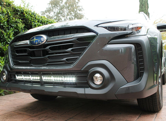 Front view of a gray SUV with a visible Subaru logo on a paved surface.