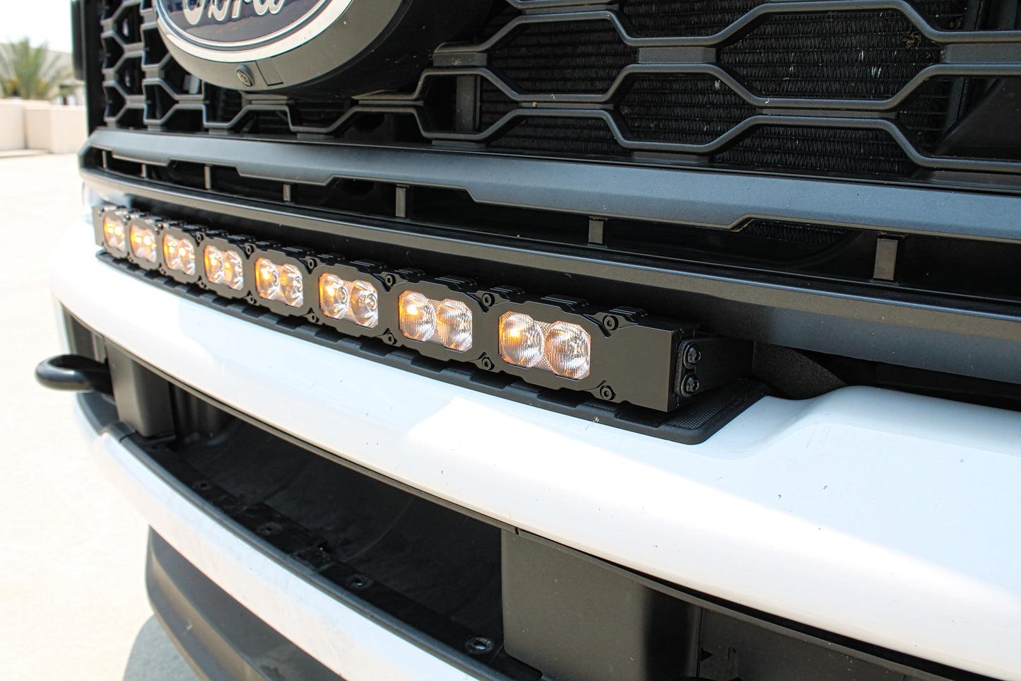 Close-up of a truck grille with a Ford logo and a mounted LED light bar.