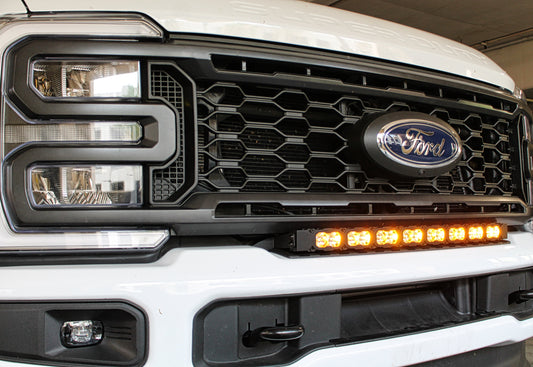 Close-up of a Ford vehicle grille with headlights and LED light bar.