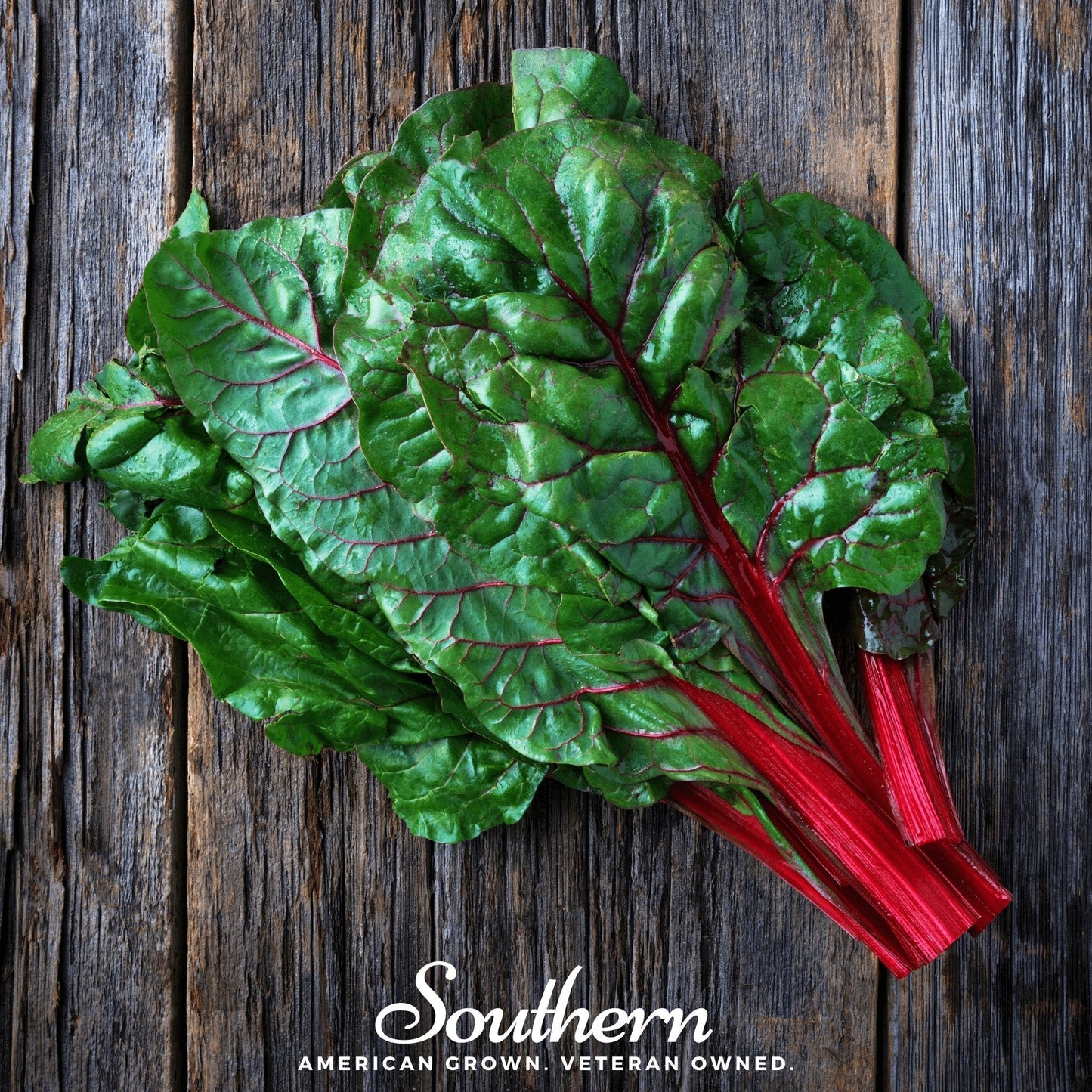 Bunch of green leafy swiss chard with red stems on a wooden surface, branded 'Southern'.