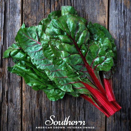 Bunch of green leafy swiss chard with red stems on a wooden surface, branded 'Southern'.