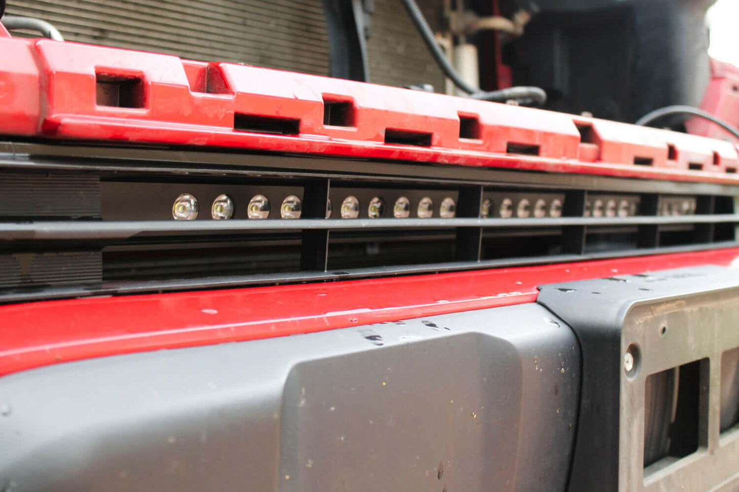 Close-up of a red and gray vehicle light bar with multiple lights.
