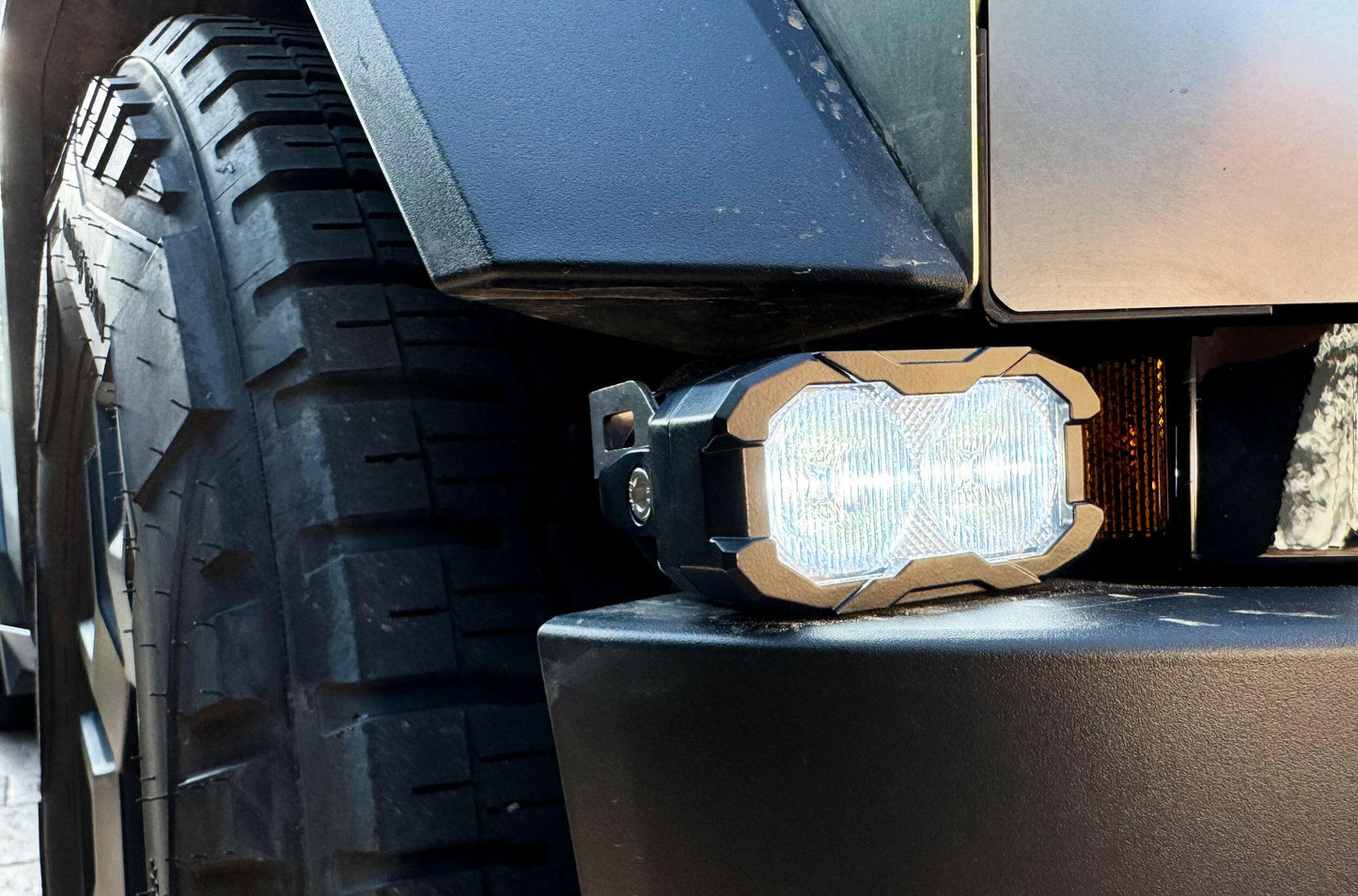 Off-road vehicle with a large tire and a mounted light on a dark background