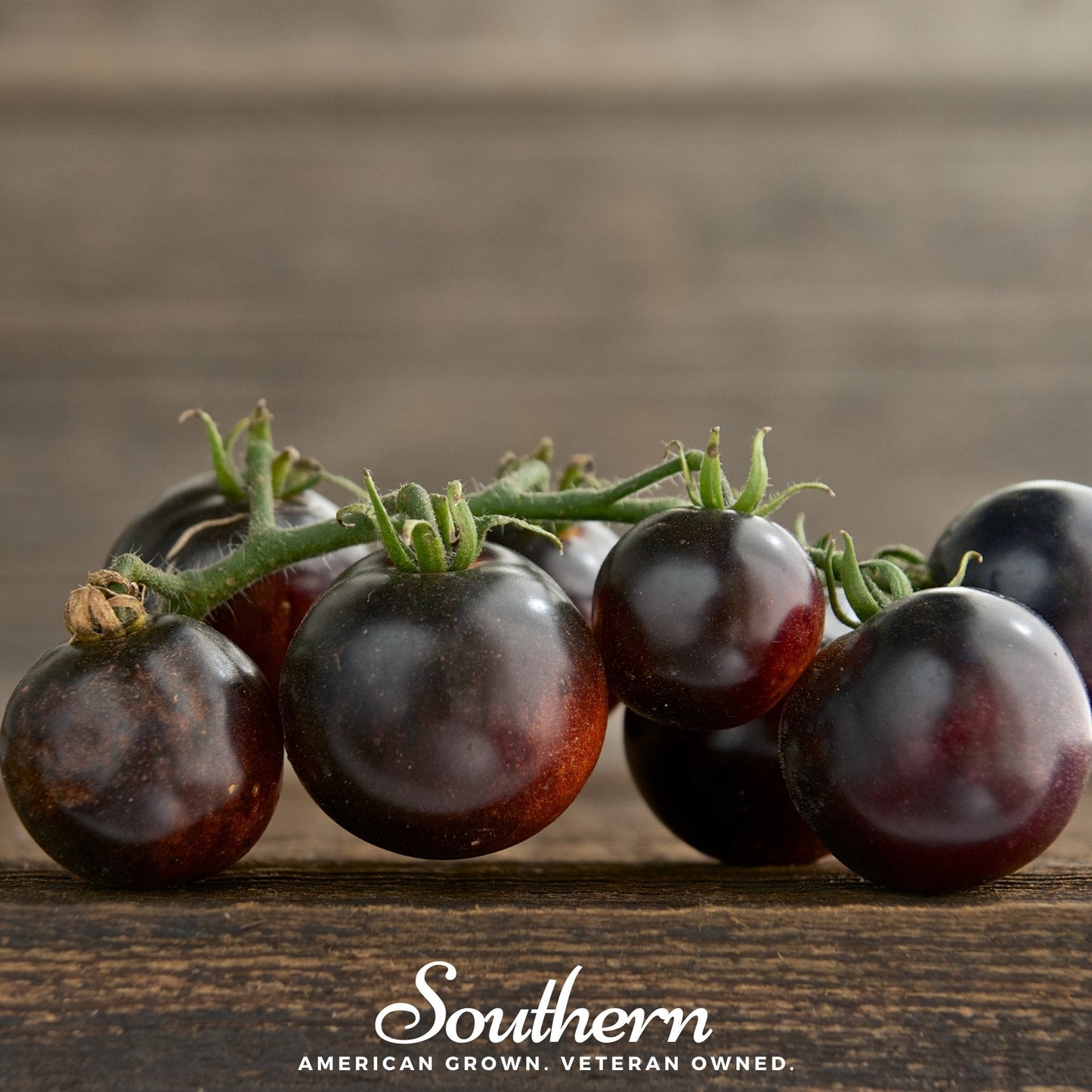 Bunch of dark purple tomatoes on a wooden surface with 'Southern' brand name.