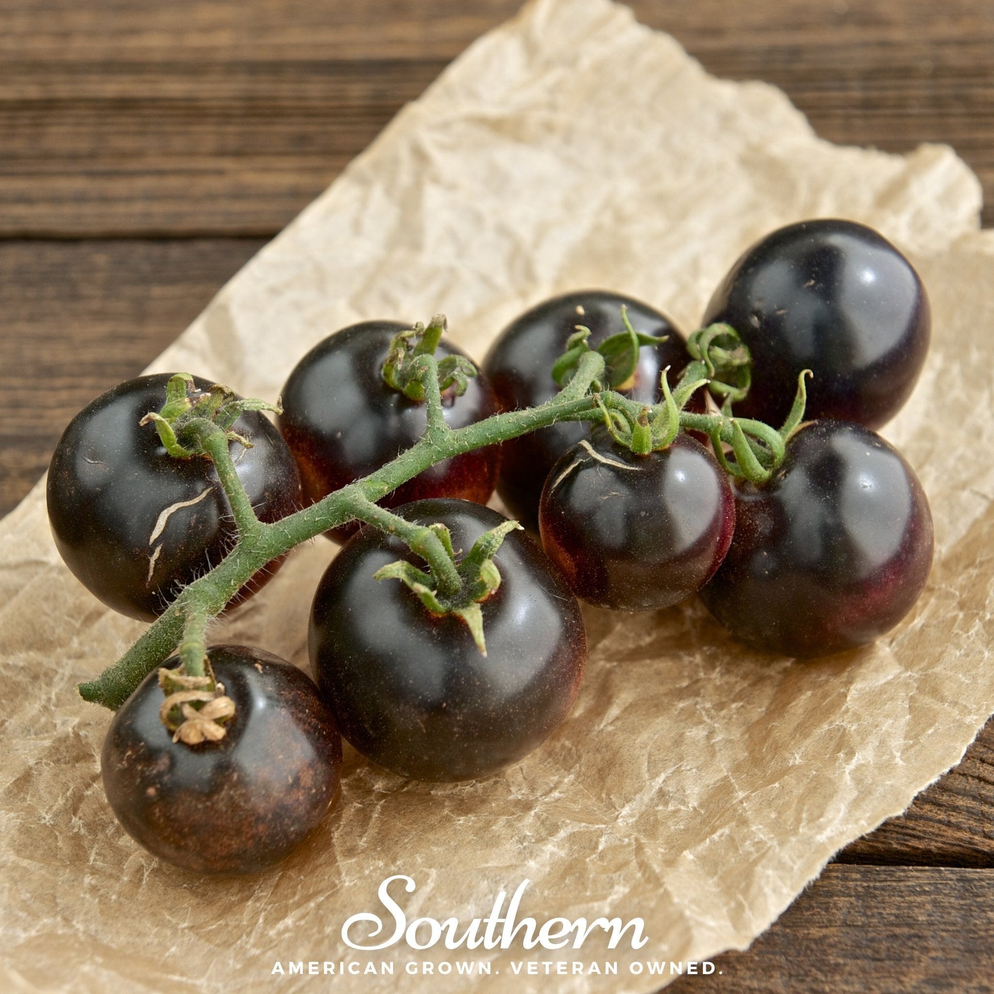 Black tomatoes on a vine with 'Southern' branding on a wooden surface