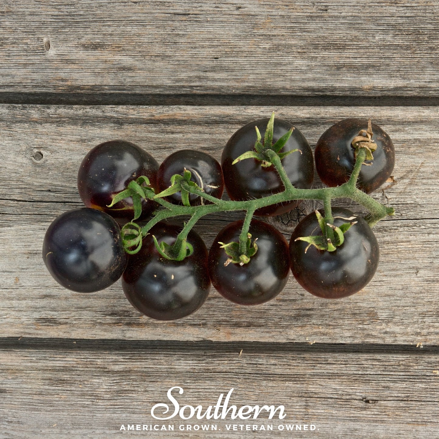Black tomatoes on a vine with 'Southern' branding on a wooden surface